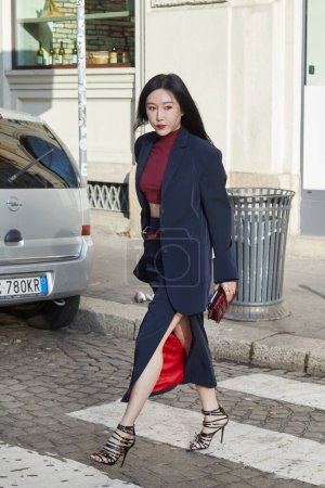 Foto de MILÁN, ITALIA - 24 DE FEBRERO DE 2024: Mujer con chaqueta azul, falda y bolso rojo Ferrari antes del desfile de moda Ferrari, Milan Fashion Week street style - Imagen libre de derechos