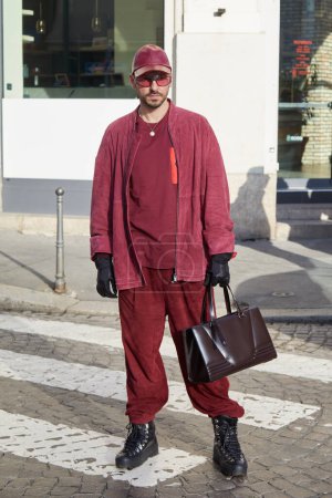 Téléchargez les photos : MILAN, ITALIE - 24 FÉVRIER 2024 : Pantalon homme en daim rouge et sac Ferrari avant le défilé de mode Ferrari, Milan Fashion Week street style - en image libre de droit