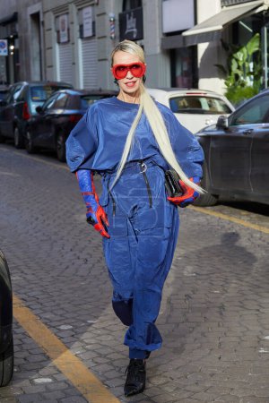 Foto de MILÁN, ITALIA - 24 DE FEBRERO DE 2024: Denisa Palsha con monos azules y gafas de sol rojas antes del desfile de moda Ferrari, Milan Fashion Week street style - Imagen libre de derechos