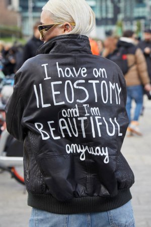 Foto de MILÁN, ITALIA - 24 DE FEBRERO DE 2024: Mujer con chaqueta de cuero negro con escritura sobre ileostomía antes del desfile de moda Ermanno Scervino, Milan Fashion Week street style - Imagen libre de derechos