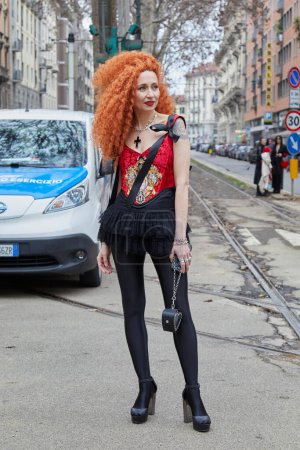 Foto de MILÁN, ITALIA - 24 DE FEBRERO DE 2024: Mujer con vestido rojo y negro y pelo rizado rojo antes de Dolce y Gabbana desfile de moda, Milan Fashion Week street style - Imagen libre de derechos