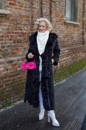 Téléchargez les photos : MILAN, ITALIE - 25 FÉVRIER 2024 : Femme avec sac Valentino rose et manteau en fourrure noire avant le défilé de mode Luisa Spagnoli, Milan Fashion Week street style - en image libre de droit