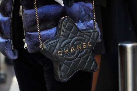 Foto de MILÁN, ITALIA - 25 DE FEBRERO DE 2024: Mujer con bolso Chanel de cuero negro en forma de estrella antes del desfile de moda Luisa Spagnoli, Milan Fashion Week street style - Imagen libre de derechos