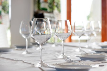 Téléchargez les photos : Aménagement de table dans un restaurant avec verres à vin mousseux en cristal et à eau, et assiettes de départ, le tout prêt pour un événement spécial ou une expérience culinaire, avec attention aux détails et à l'ambiance - en image libre de droit