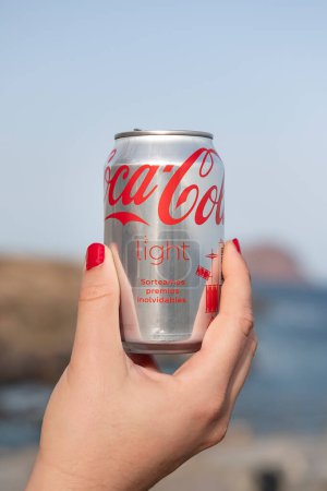 Foto de Los Abrigos, Tenerife, Islas Canarias, España - 9 de agosto de 2023: mujer sosteniendo en su mano una lata de Coca-Cola Light, con la marca visible del refresco carbonatado producido por The Coca-Cola Company - Imagen libre de derechos