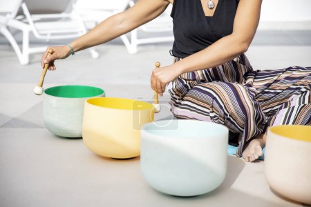 Sound healer using rubber mallets on crystal singing bowls to produce pure, clean tones which are thought to promote overall well-being, balancing the chakras through an immersive auditory experience