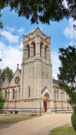 Foto de Vista de la torre de la iglesia de Santa María enmarcada por árboles situados en Woburn, ciudad y parroquia civil popular por un parque de safari de vida silvestre y una casa de campo histórica conocida como Abadía de Woburn, Bedfordshire, Reino Unido - Imagen libre de derechos