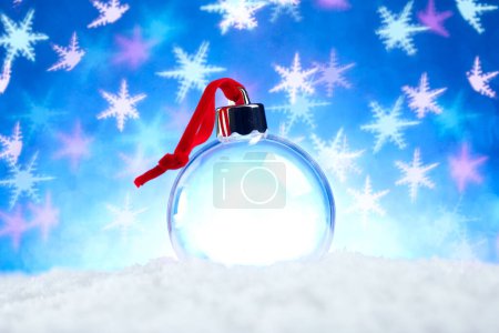Téléchargez les photos : Décoration de Noël vide clair avec ruban rouge assis dans la neige avec des lumières bleues brillantes fond bokeh flocon de neige - en image libre de droit
