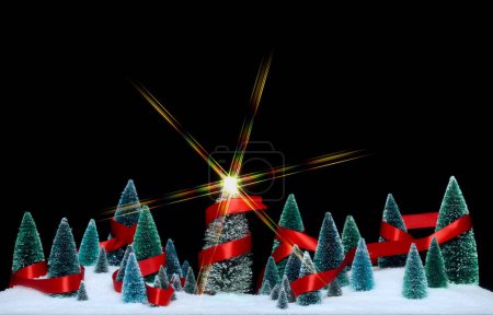 Téléchargez les photos : Décorations d'arbres miniatures enveloppées dans un ruban rouge brillant avec étoile scintillante sur l'arbre de Noël. - en image libre de droit