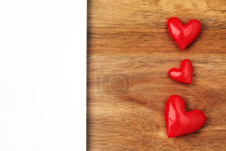 Foto de Shiny red hearts on wooden background with empty card - Imagen libre de derechos
