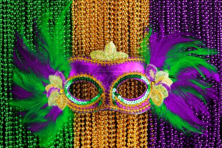 Foto de Cuentas Mardi Gras verdes, doradas y púrpuras con fondo de máscara - Imagen libre de derechos