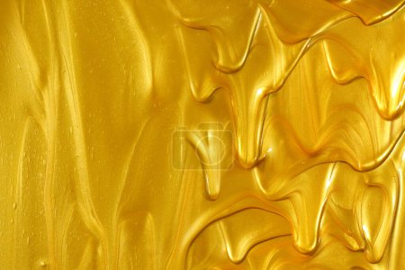 Téléchargez les photos : Peinture dorée métallique brillante brillante coulant et coulant vers le bas, formant un fond doré avec un espace de copie vide. - en image libre de droit