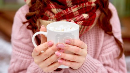 Photo for Banner closeup cacao cup in hands. woman in checkered scarf drink hot coffee with marshmallow. - Royalty Free Image