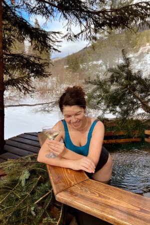 Photo for Woman with glass of white wine in outdoor hot tub in the mountains for spa and relaxation. therapeutic effects of hydrotherapy - Royalty Free Image