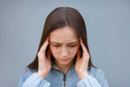 Photo for Teen girl suffering of headache on blue gray background. Troubled generation z female suffers from crisis of misunderstanding with parents - Royalty Free Image