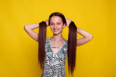 Foto de Cuidado del cabello largo adecuado en verano, chica adolescente hacer colas de caballo sobre fondo amarillo. pelo sin puntas abiertas - Imagen libre de derechos