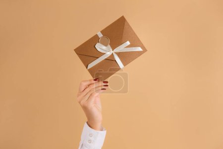 Foto de Tarjeta de descuento de mano femenina o certificado de regalo en sobre sobre sobre fondo beige - Imagen libre de derechos