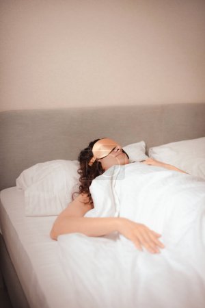 woman in beige silk sleep mask sleep in bed in hotel. Improving sleep quality