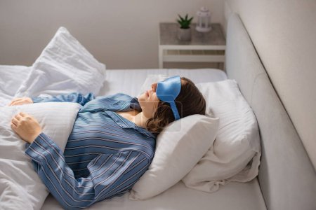 Frau schläft schnell im Bett. Schlafmaske gegen Schlaflosigkeit