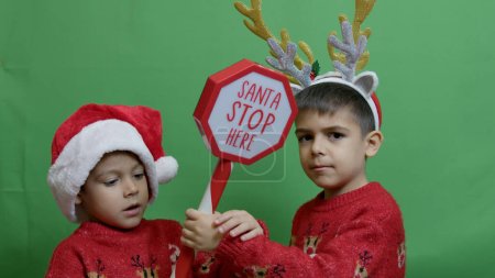 Photo for Naughty brothers inviting santa to come. Dancing and grabbing the sign. High quality photo - Royalty Free Image