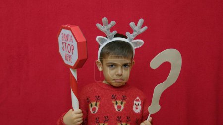 Trauriger Kind ungezogener Junge, der fragt, ob der Weihnachtsmann zu Weihnachten kommt. Hochwertiges Foto