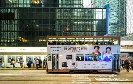 Téléchargez les photos : Hong Kong, île de Hong Kong, 27 janvier 2024. Vue d'un tramway blanc à un arrêt de tramway annonçant la société de mode Céline dans le quartier central. - en image libre de droit