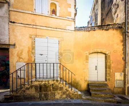 Téléchargez les photos : Arles, France, 9 septembre 2023, vue de deux entrées pour une ancienne maison murale ocre rue des Arenes - en image libre de droit