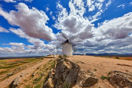 Foto de Molino de viento en las colinas de Consuegra, región de Toledo, Castilla La Mancha, España. Ruta del Quijote con molinos de viento. Paisaje de verano con cielo azul y nubes. - Imagen libre de derechos