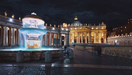 Téléchargez les photos : Vatican City (Holy See. Fountain in front of St. Peter's Basil cathedral on Saint Square. Nighttime, blue hour night sky street lamps. Rome, Italy. Famous travel destination and touristic landmark - en image libre de droit