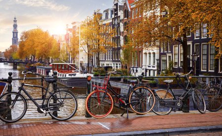 Bicicleta sobre canal Amsterdam ciudad otoño amarillo hoja caída. Pintoresco paisaje urbano en Holanda con vista al río Amstel