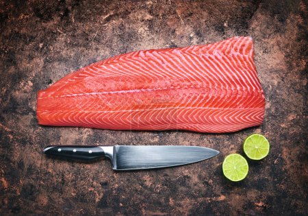 Foto de Filete de pescado rojo salmón fresco en mesa grunge rústica con cuchillo y - Imagen libre de derechos
