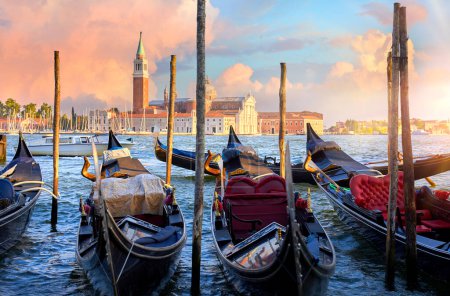 Photo for Venice, Italy. View at San Giorgio Maggiore from the Marco Square with Venetian gondolas moored by pear floating on water of Grand Canal. Scenic sunset in venice city. - Royalty Free Image