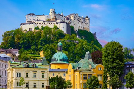 Photo for Salzburg, Austria. White Fortress medieval castle at cliff under the old town. Famous landmark with blue summer sky and green trees. Beautiful european architecture. - Royalty Free Image