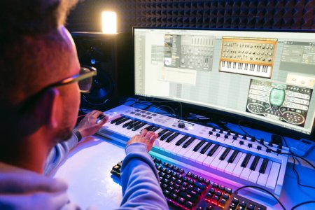 Producer, audio engineer uses a control panel and screen to record a track of a new album in a recording studio, in a soundproof room. Image producer, designer in working process