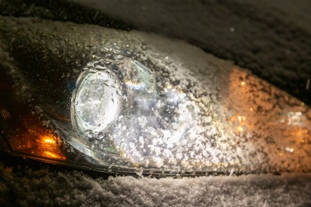 Téléchargez les photos : Phare avant de voiture lors de la nuit givrée, saison des neiges avec neige - en image libre de droit