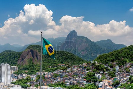 Brasilianische Flagge im Vordergrund und Christus mit Blick auf die Favela in Rio De Janeiro, Brasilien