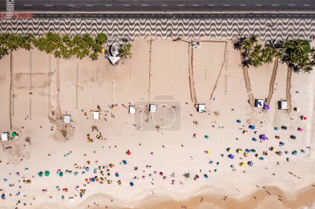 Téléchargez les photos : Vue aérienne sur la plage de Copacabana avec des personnes se relaxant sur la plage et des palmiers près de la célèbre promenade en bois - en image libre de droit