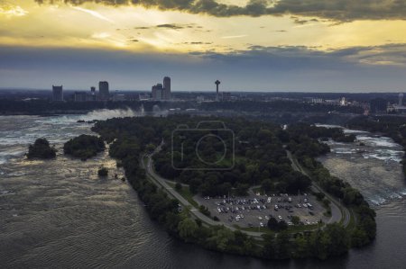 Téléchargez les photos : Panorama aérien des chutes du Niagara avec de hauts bâtiments traversant la rivière Niagara au coucher du soleil. Paysage nuageux chaud - en image libre de droit