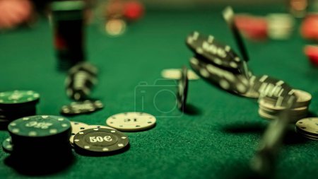 Téléchargez les photos : A man's hand is seen tossing gambling poker chip onto a green, textured table. Conveys the concept of gambling and card games. - en image libre de droit