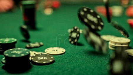 Téléchargez les photos : A man's hand is seen tossing gambling poker chip onto a green, textured table. Conveys the concept of gambling and card games. - en image libre de droit