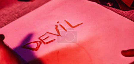 Photo for A close-up shot of a paper with the word 'Devil' written in cursive handwriting, creating a mysterious and intriguing atmosphere - Royalty Free Image