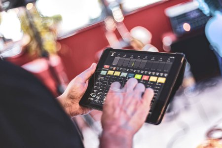 Foto de Captura detallada de la mano de un ingeniero de sonido haciendo ajustes en una tableta durante una actuación en vivo. - Imagen libre de derechos