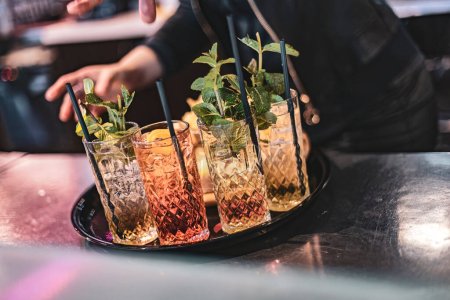 Un impresionante primer plano de cócteles y bebidas elaborados por expertos, bellamente exhibidos en vasos de cristal en una bandeja.