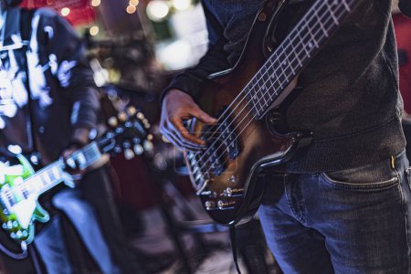 Photo for Close-up shot of a bassist's hands playing the bass guitar, fingers plucking and strumming the strings. - Royalty Free Image