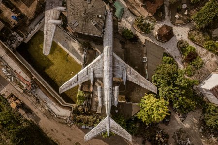 Foto de Una cautivadora foto aérea de un avión abandonado tomada desde una perspectiva de arriba hacia abajo, revelando su aislamiento y decadencia. - Imagen libre de derechos