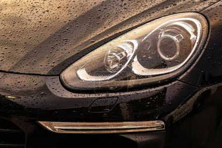 A striking close-up shot of a high-end luxury car's front headlight shining brilliantly.