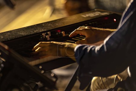 Foto de Primer plano de las manos de un pianista tocando apasionadamente en un concierto nocturno nublado y atmosférico. - Imagen libre de derechos