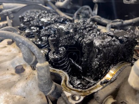 Motor de coche empanado con residuos y alquitrán, un símbolo de mantenimiento deficiente que necesita reparación.