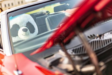 Un peluche panda câlin se trouve sur le siège d'une voiture vintage américaine classique, évoquant la nostalgie.