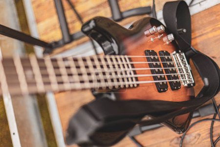 An electric bass guitar is securely hanging on a wall, displaying its sleek design and strings.